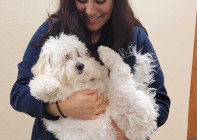 Vet tech cradles white puppy.